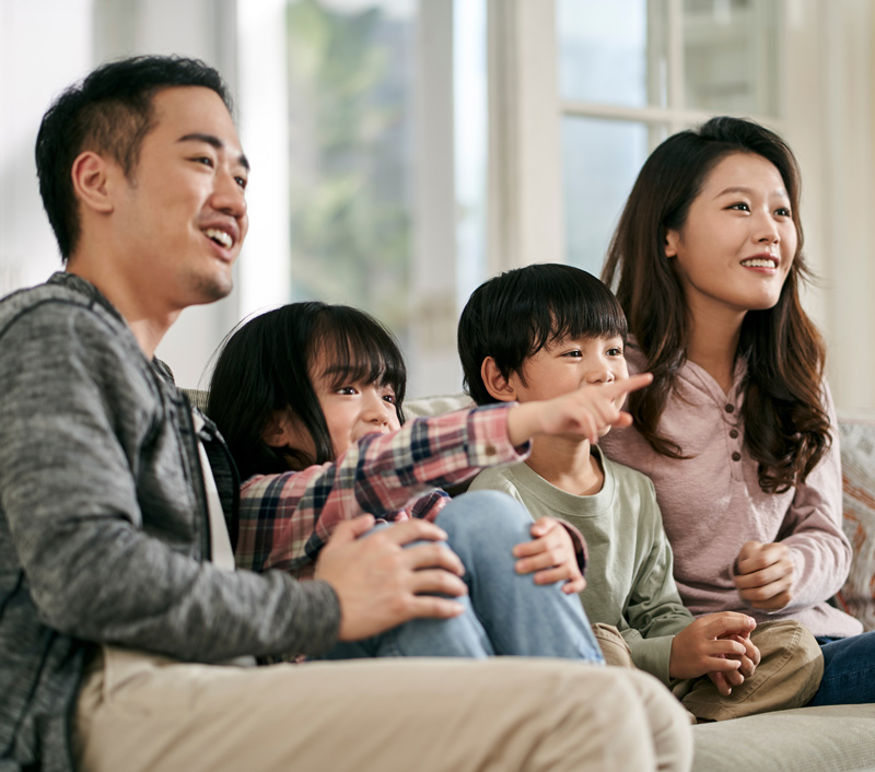 Family sitting on a couch together. Mother, father, and two children.